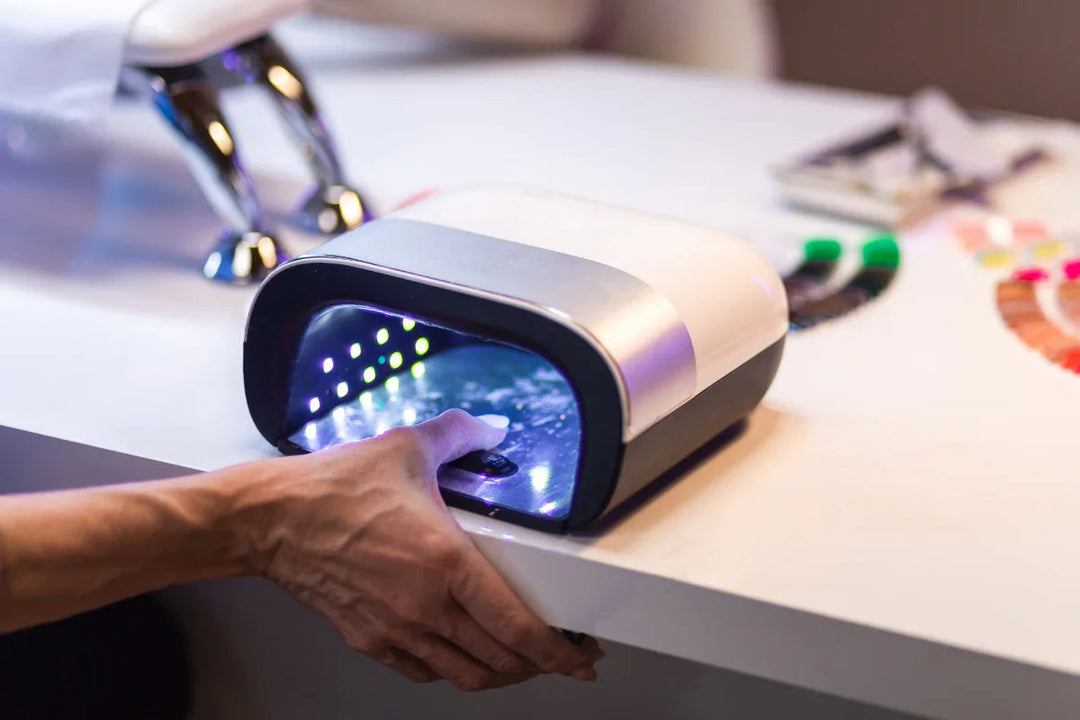 Mano usando lámpara UV LED para secar uñas en salón de manicura moderno